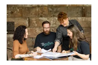 Natalie Sheild and her team of consultants gather around a table to discuss restaurant openings and business consulting